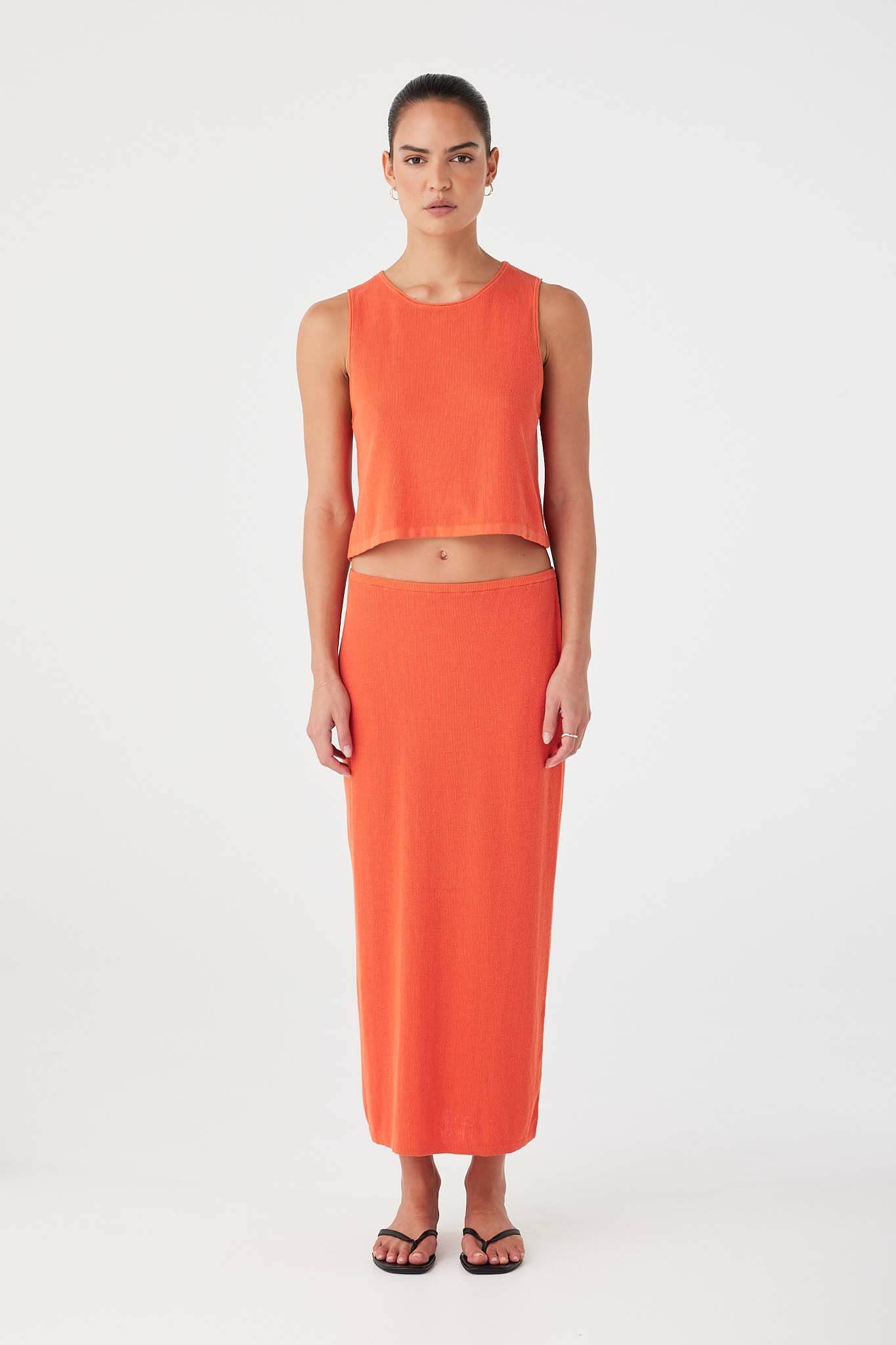 Model wearing orange (mandarin) rib knit tank in organic cotton hemp blend with relaxed fit and rolled edges.