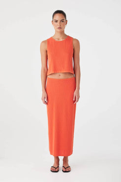Model wearing orange (mandarin) rib knit tank in organic cotton hemp blend with relaxed fit and rolled edges.