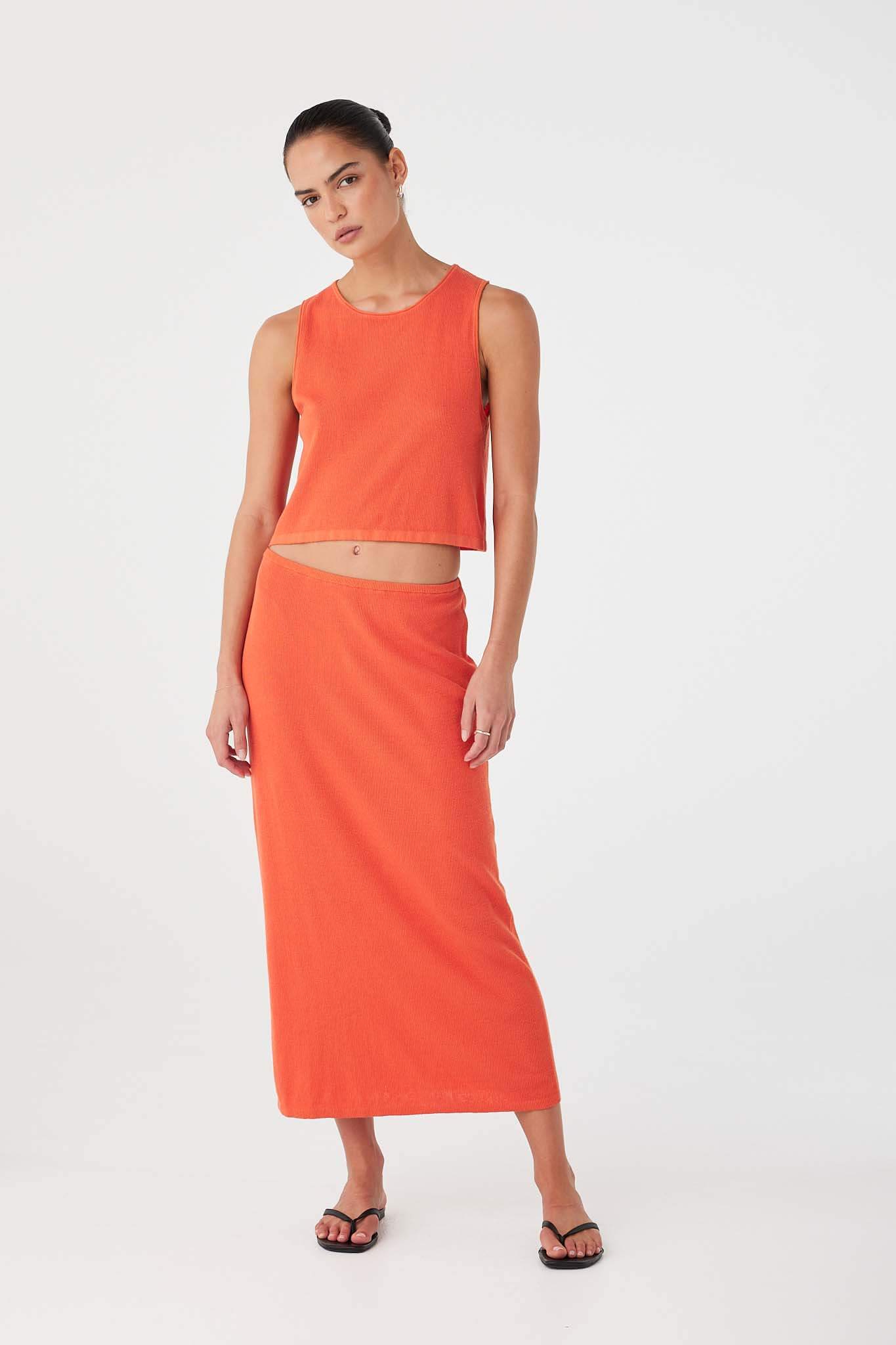 Model in matching Theo Tank and Skirt set in orange (mandarin), rib knit crafted from organic cotton hemp blend.