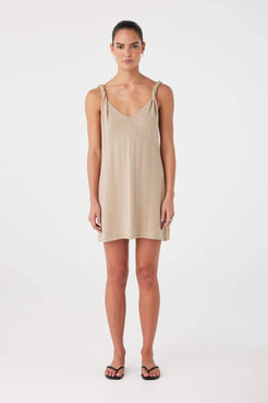 Model wearing taupe linen–cotton mini dress with twist straps, V neckline, and semi-fitted silhouette.