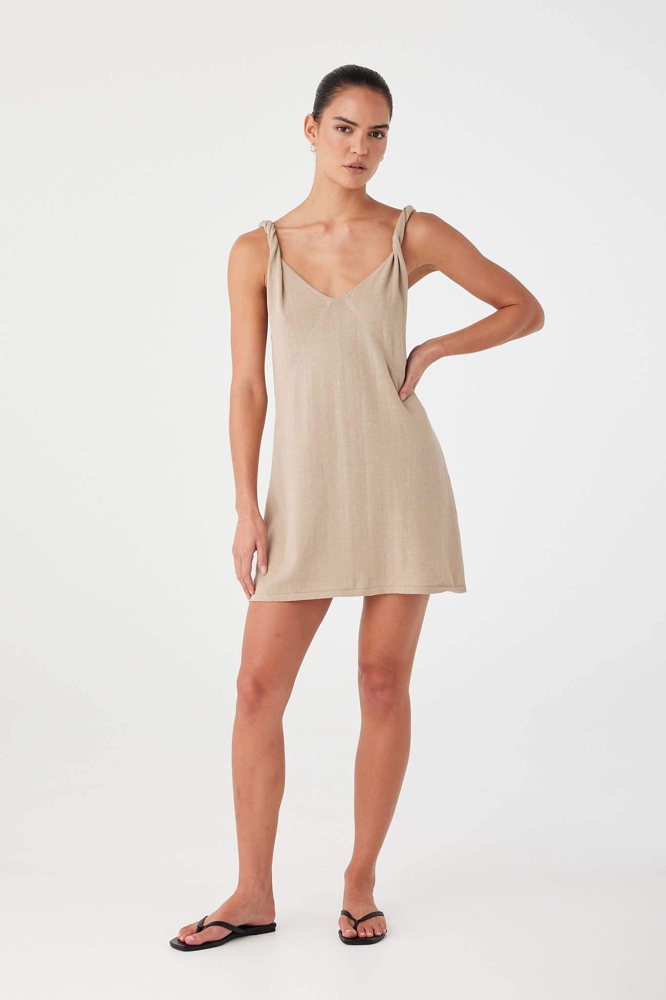 Model styling taupe linen–cotton mini dress with semi-fitted shape, designed for summer ease.