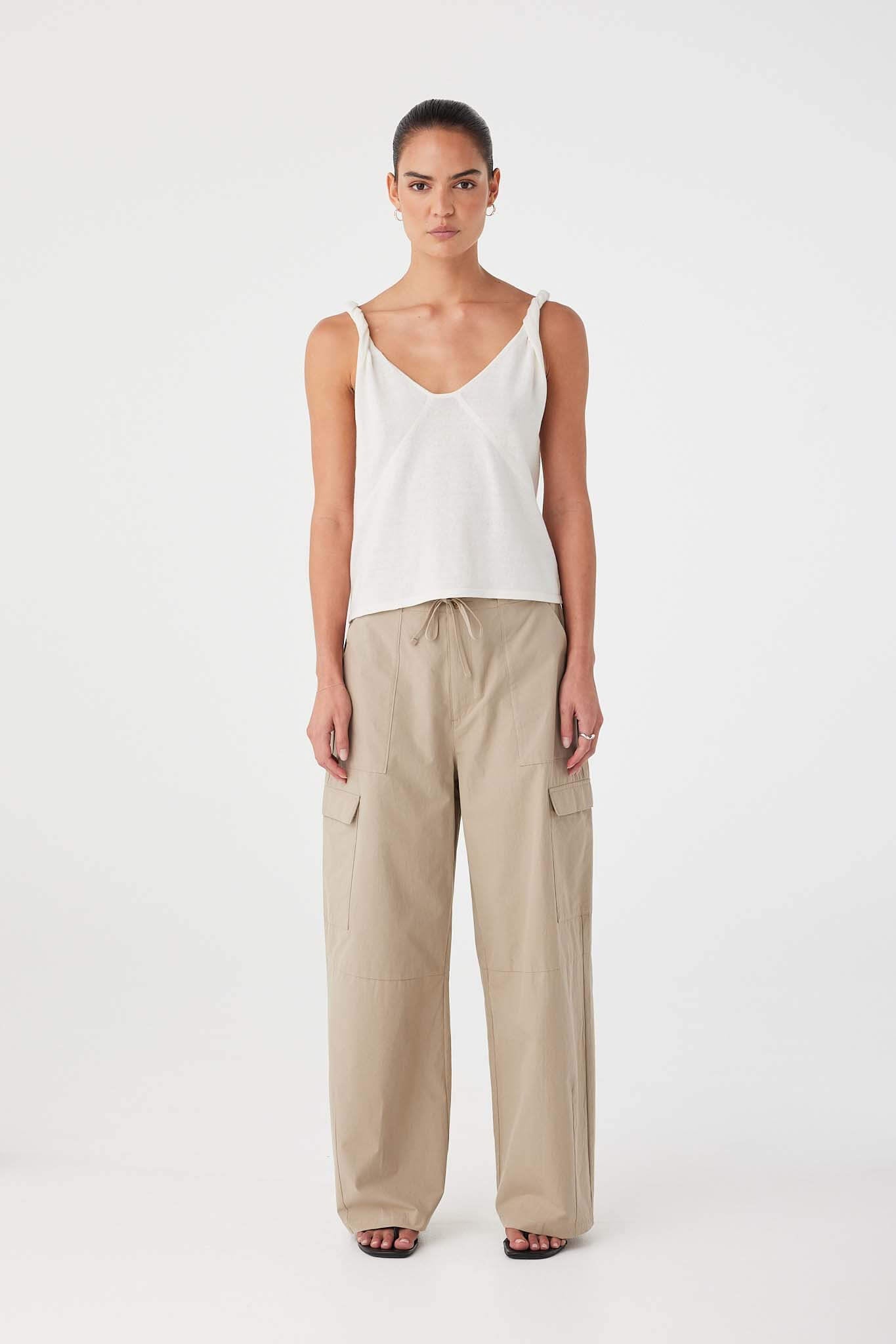Model wearing taupe barrel-leg cotton pants with relaxed fit and patch pockets, styled with a simple white tank.