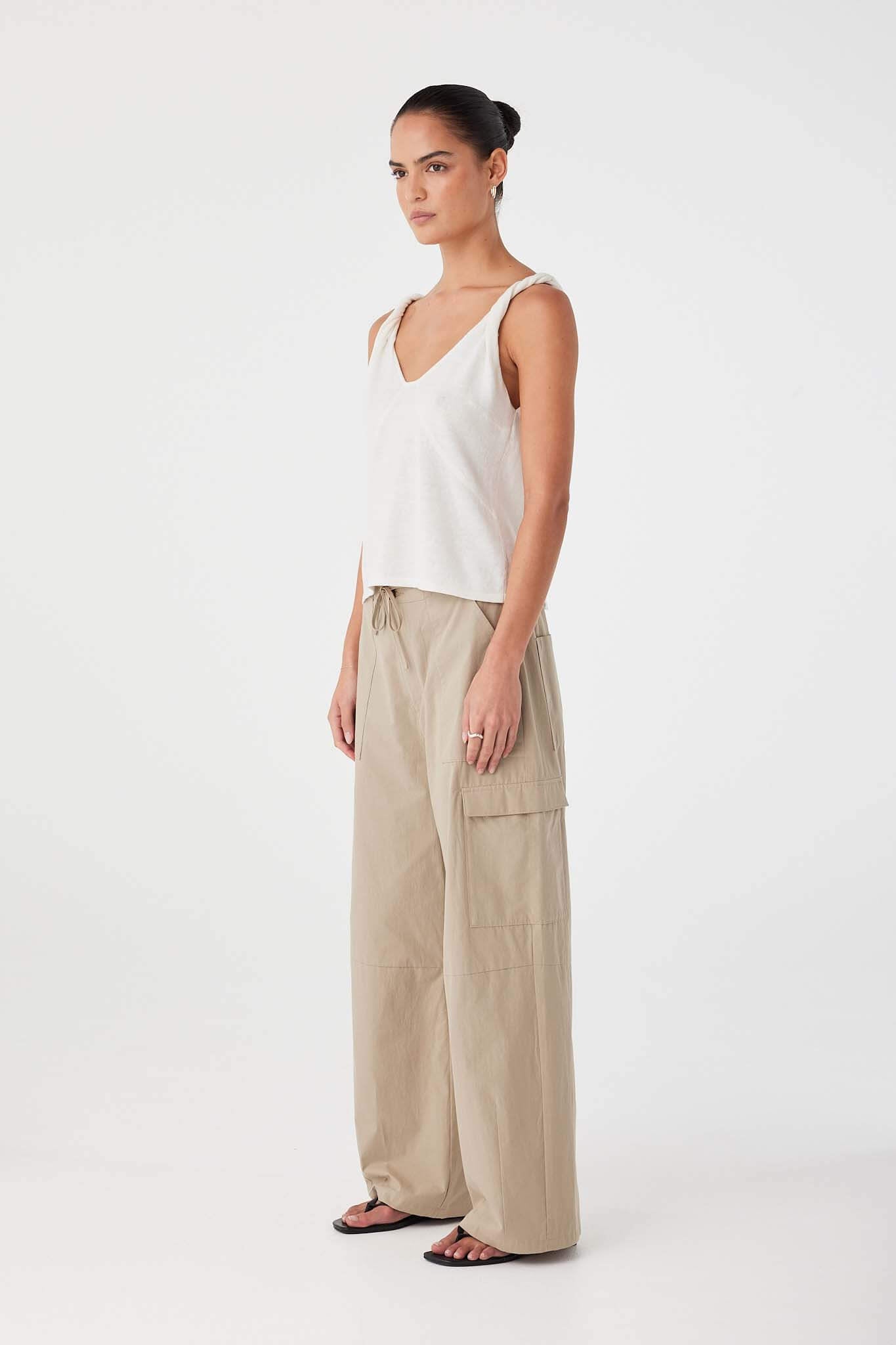 Side profile of cream tank top in linen–organic cotton blend with twisted strap detail and natural drape.