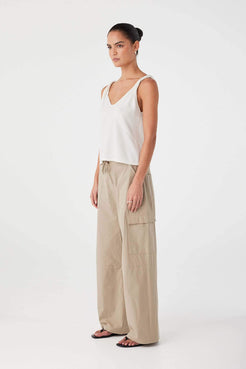 Side profile of cream tank top in linen–organic cotton blend with twisted strap detail and natural drape.