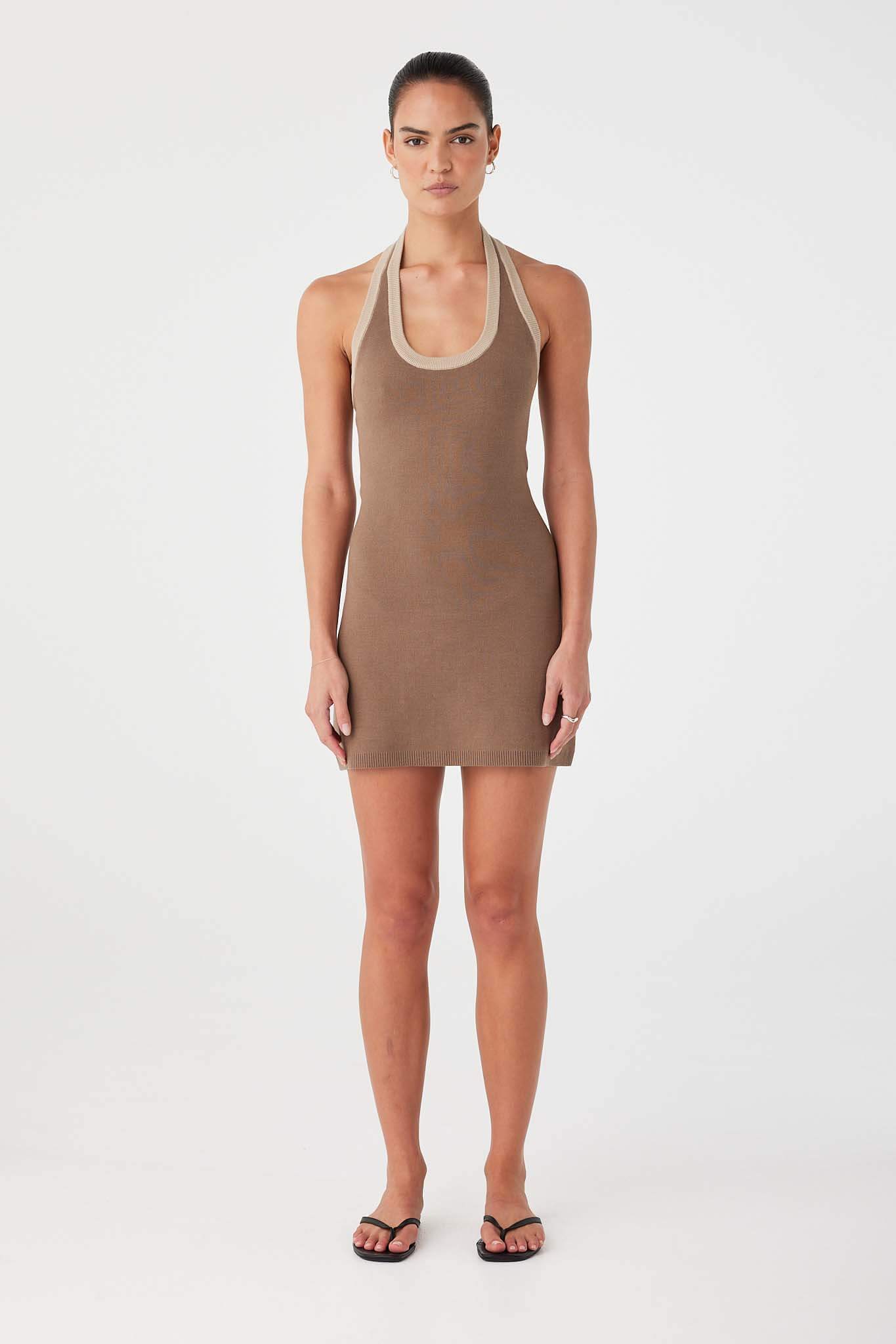 Model wearing cacao brown fitted A-line mini dress in organic cotton knit with halter neckline.