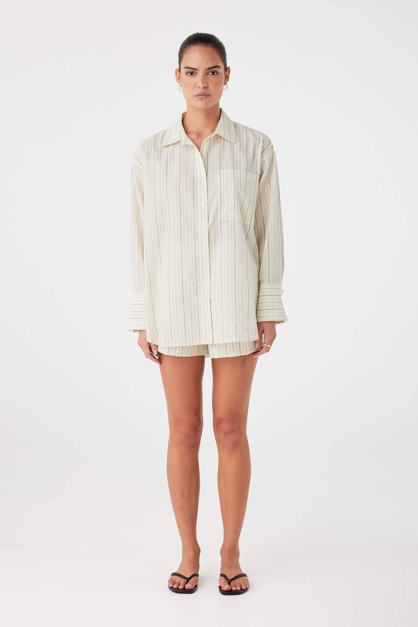 Model wearing oversized olive stripe cotton shirt with button-down front and classic collar.