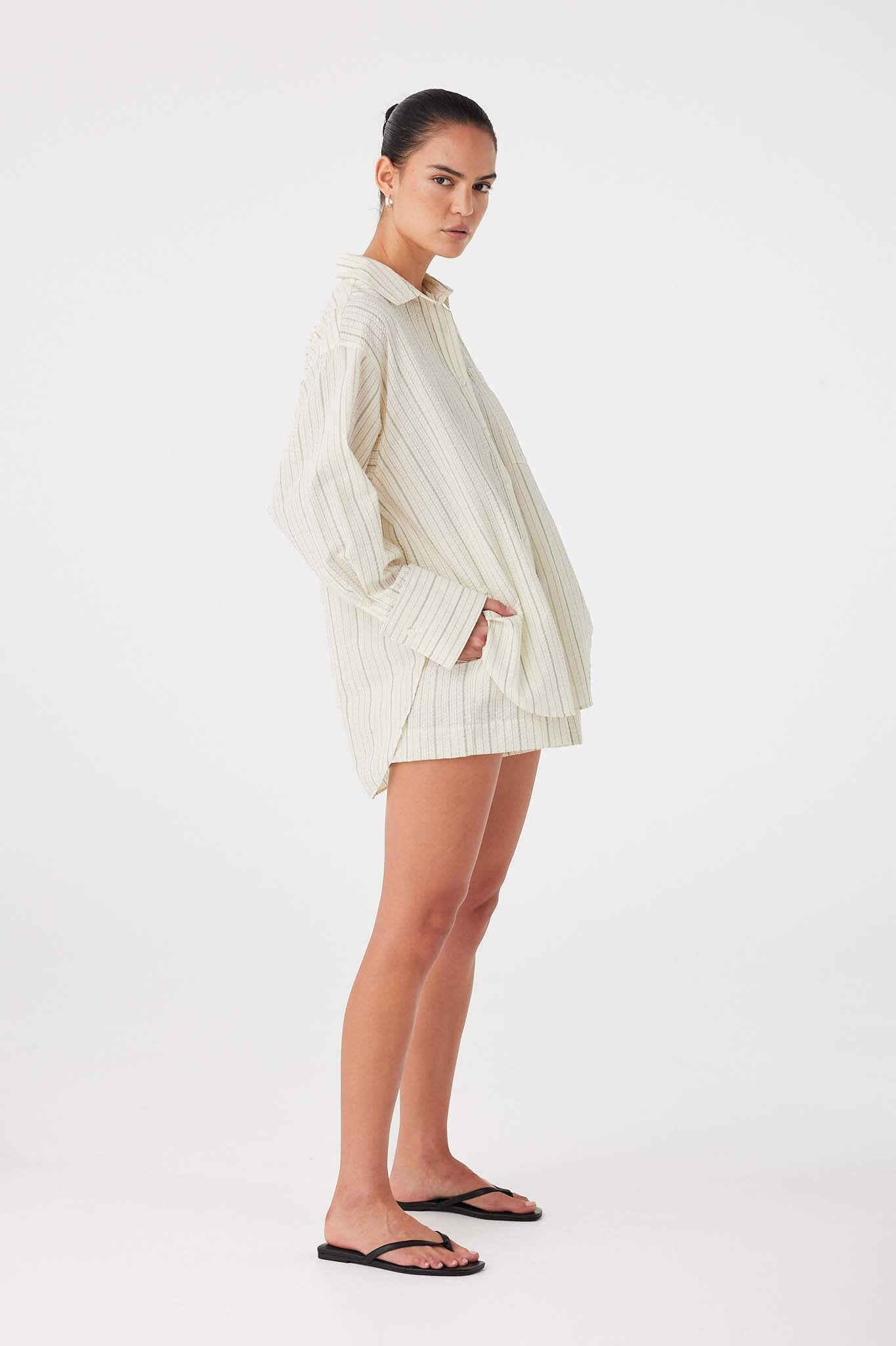 Model styling olive stripe cotton boxer shorts with oversized shirt for a coordinated summer set.