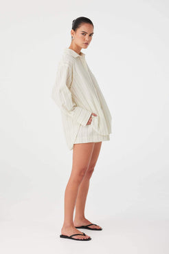 Model styling olive stripe cotton boxer shorts with oversized shirt for a coordinated summer set.