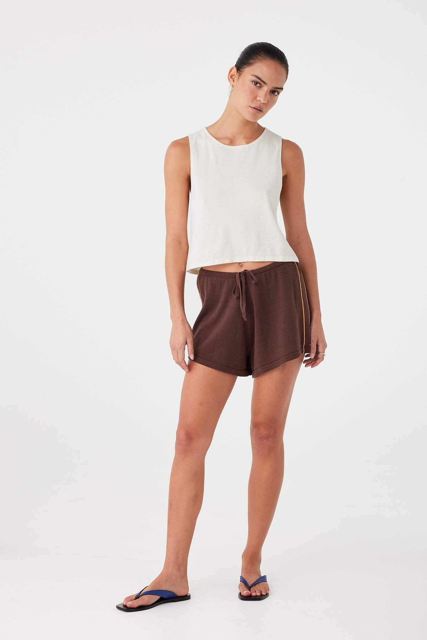 Model in espresso linen cotton drawstring shorts styled with cream tank, designed for lightweight summer wear.