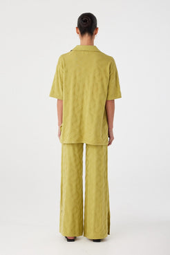 Back view of wide-leg knit pants in breathable organic cotton. Subtle texture and longline cut for effortless layering.