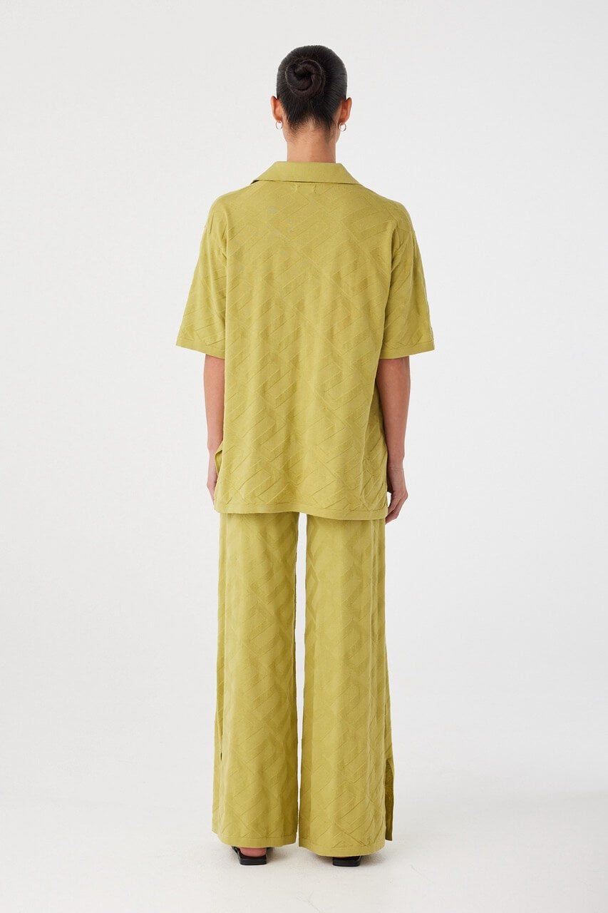 Back view of wide-leg knit pants in breathable organic cotton. Subtle texture and longline cut for effortless layering.