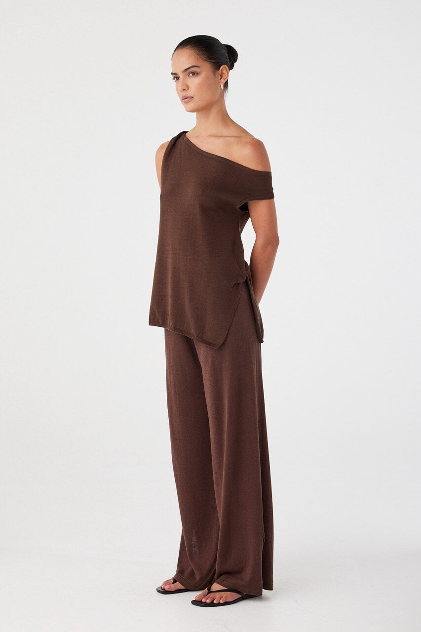 Brown off-shoulder cotton knit top with asymmetric cut, side twist detail, and lightweight drape.
