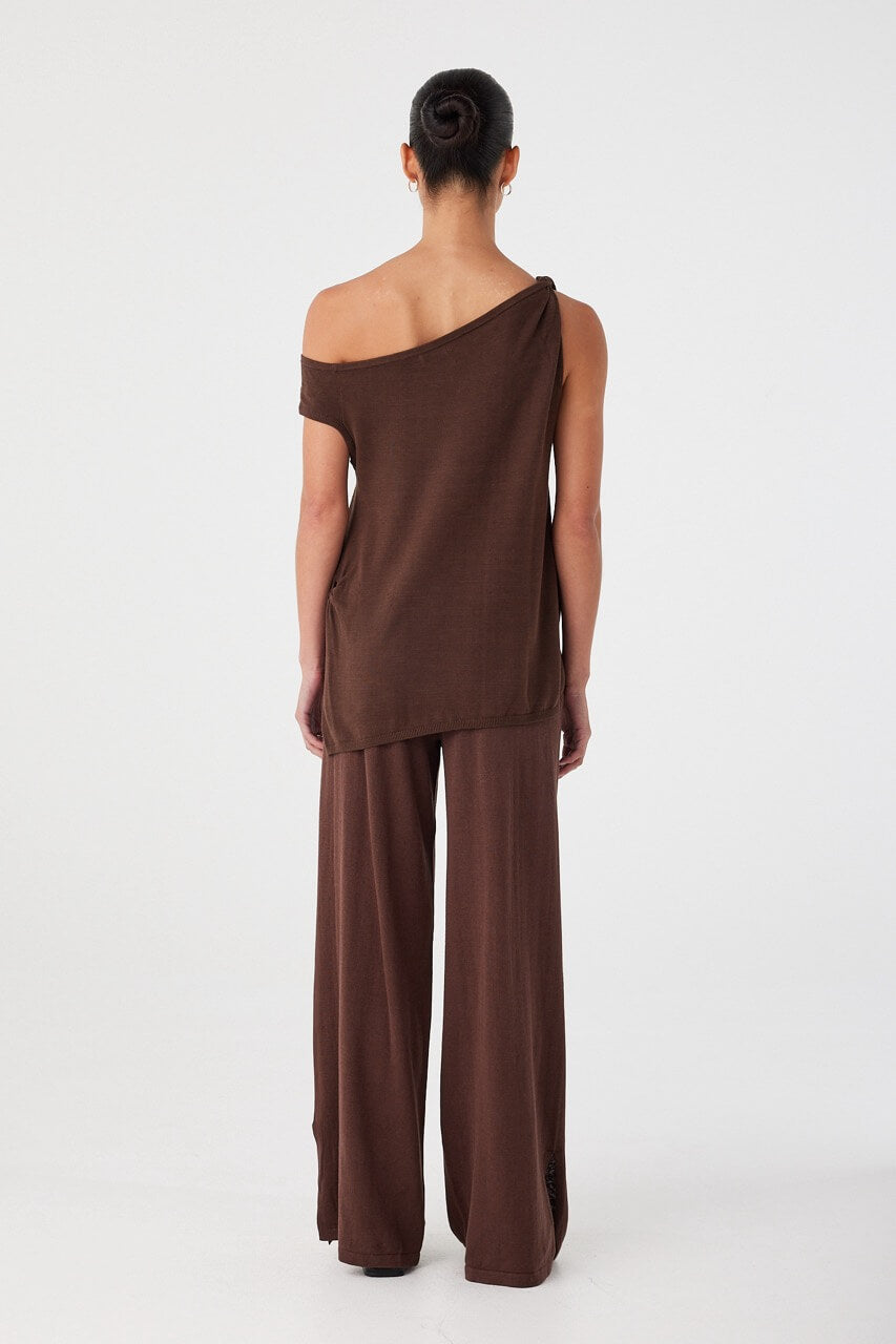 Back view of brown cotton knit asymmetric top with longline silhouette and off-shoulder neckline.