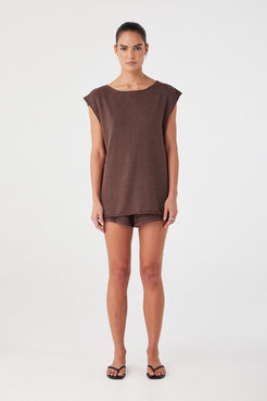 Model wears espresso brown relaxed-fit shorts in a lightweight linen–cotton blend. Mid-rise with clean, minimal silhouette.