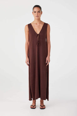 Model wears chocolate brown maxi dress with deep V neckline and tie detail. Relaxed fit in breathable linen–cotton blend.