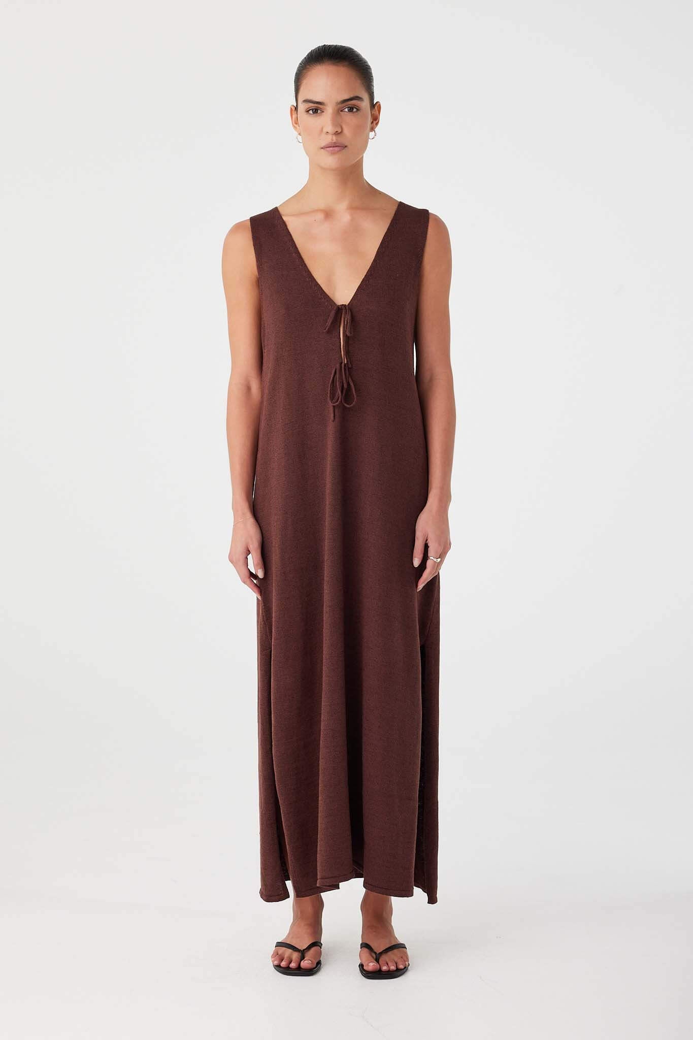 Model wears chocolate brown maxi dress with deep V neckline and tie detail. Relaxed fit in breathable linen–cotton blend.