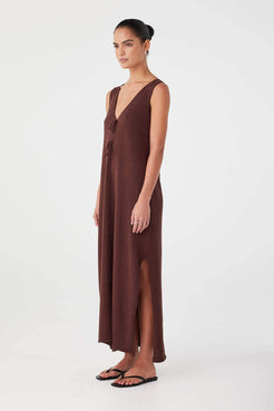 Side profile of chocolate linen–cotton dress with airy drape and deep hem split. Lightweight for warm-weather wear.