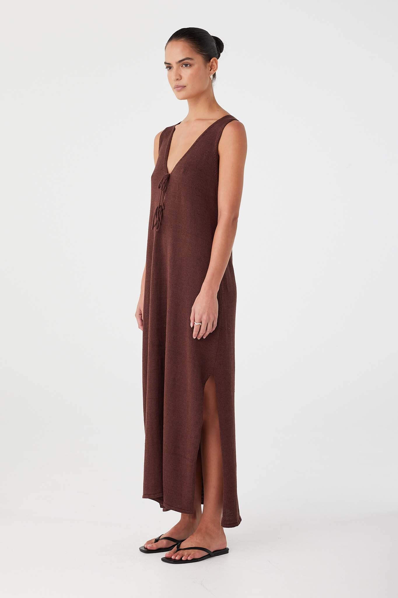 Side profile of chocolate linen–cotton dress with airy drape and deep hem split. Lightweight for warm-weather wear.