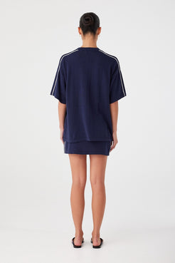 Back view of oversized navy tee with contrast shoulder stripe. Loose silhouette in breathable linen cotton knit.