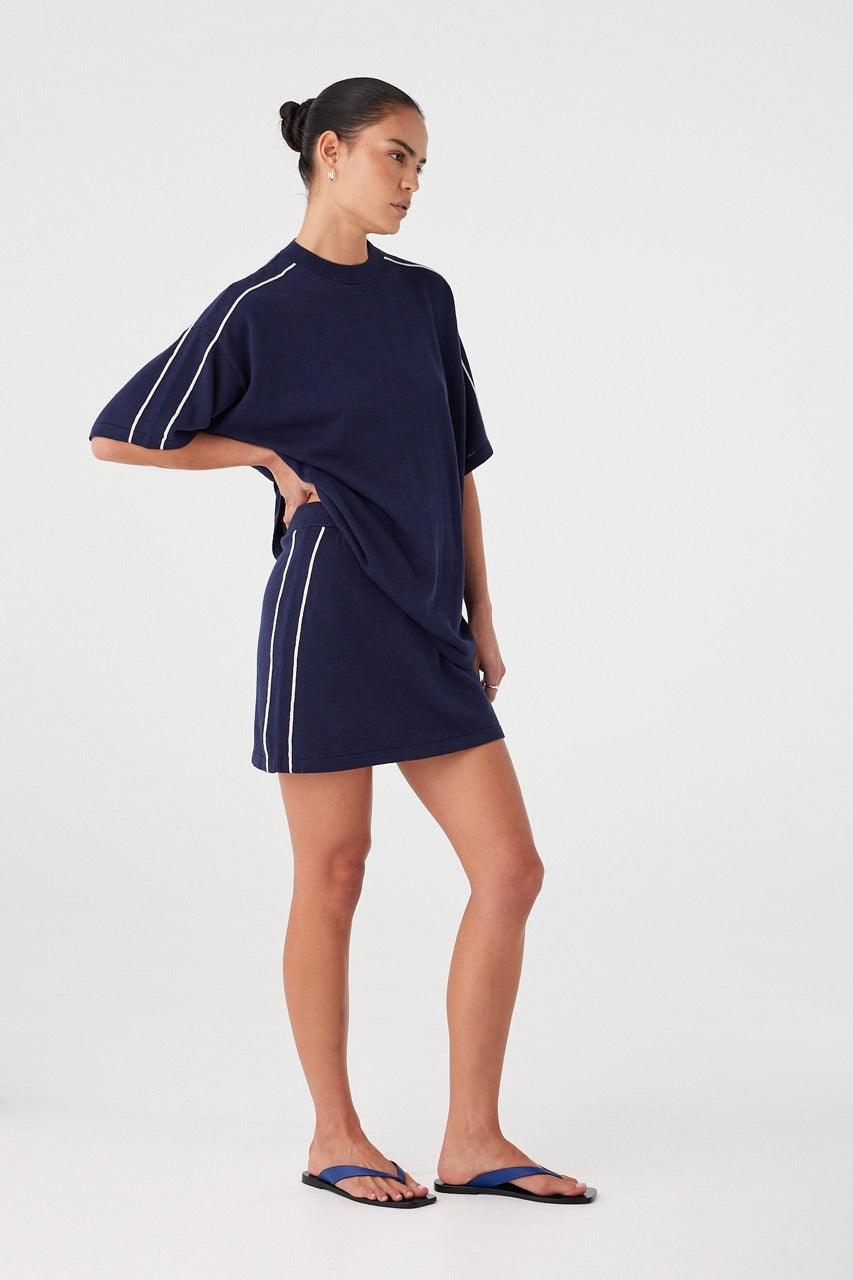 Model in navy mini skirt and matching tee. Breathable knit with subtle sport detailing, ideal for warm-weather layering sets.