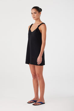 Side profile of lightweight black mini dress with subtle shaping and breathable drape. Ideal for summer layering or resort dressing.