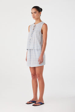 Side profile of powder blue check cotton blouse with gathering and sleeveless cut. Designed for breathability and movement.
