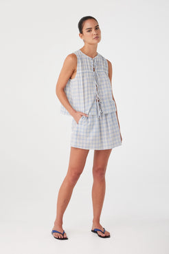 Model styled in powder blue check mini skirt with relaxed drape and high-rise fit. Lightweight texture ideal for layering.