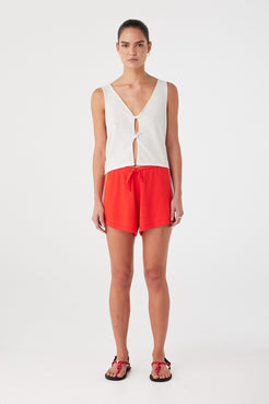 Model wears relaxed linen cotton shorts with soft drape and drawcord waist, styled for warm days.