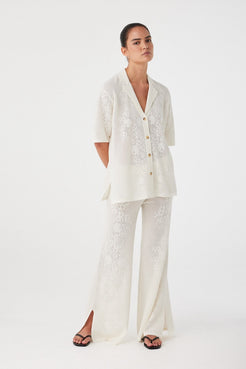 Wide-leg pants in cream crochet styled with matching shirt. Lightweight texture and soft flow ideal for summer layering sets.