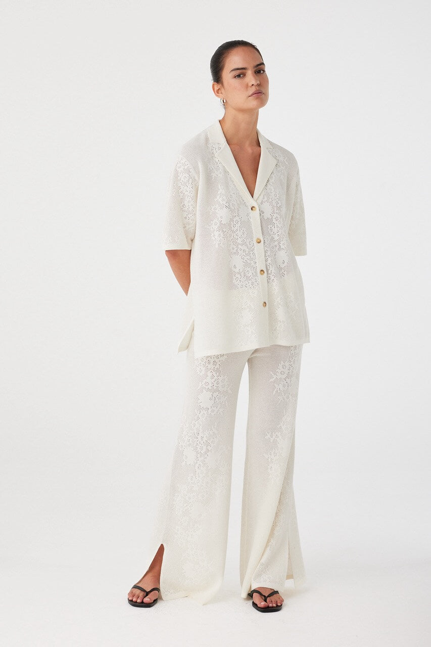 Wide-leg pants in cream crochet styled with matching shirt. Lightweight texture and soft flow ideal for summer layering sets.