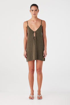 Model wears olive green mini dress with subtle sparkle. V neckline with two front ties and shaping seams in a lightweight knit.