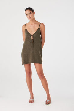 Model in olive sparkle mini dress with V neckline and tie detail. Shaping seams and soft silhouette ideal for summer styling.