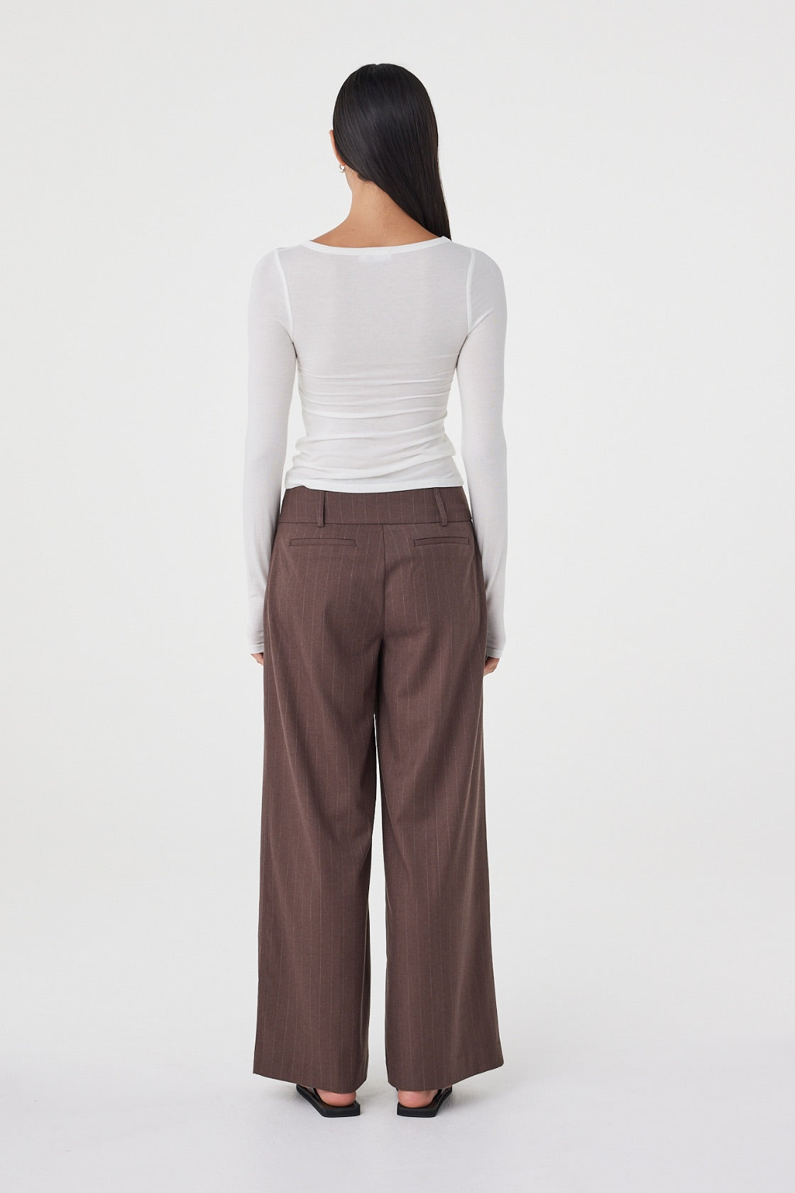 Back view of the Manon Pant in Espresso Pinstripe featuring the wide-leg fit and non-functional back welt pockets.