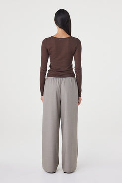 Back view of the Annika Pant in taupe blue pinstripe paired with a fitted brown long sleeve top, highlighting the relaxed fit and fluid movement through the leg