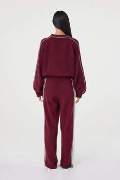 Back view of the Nella Zip in merlot and cream showcasing the relaxed silhouette, ribbed waistband and contrast cream piping running along the sleeves