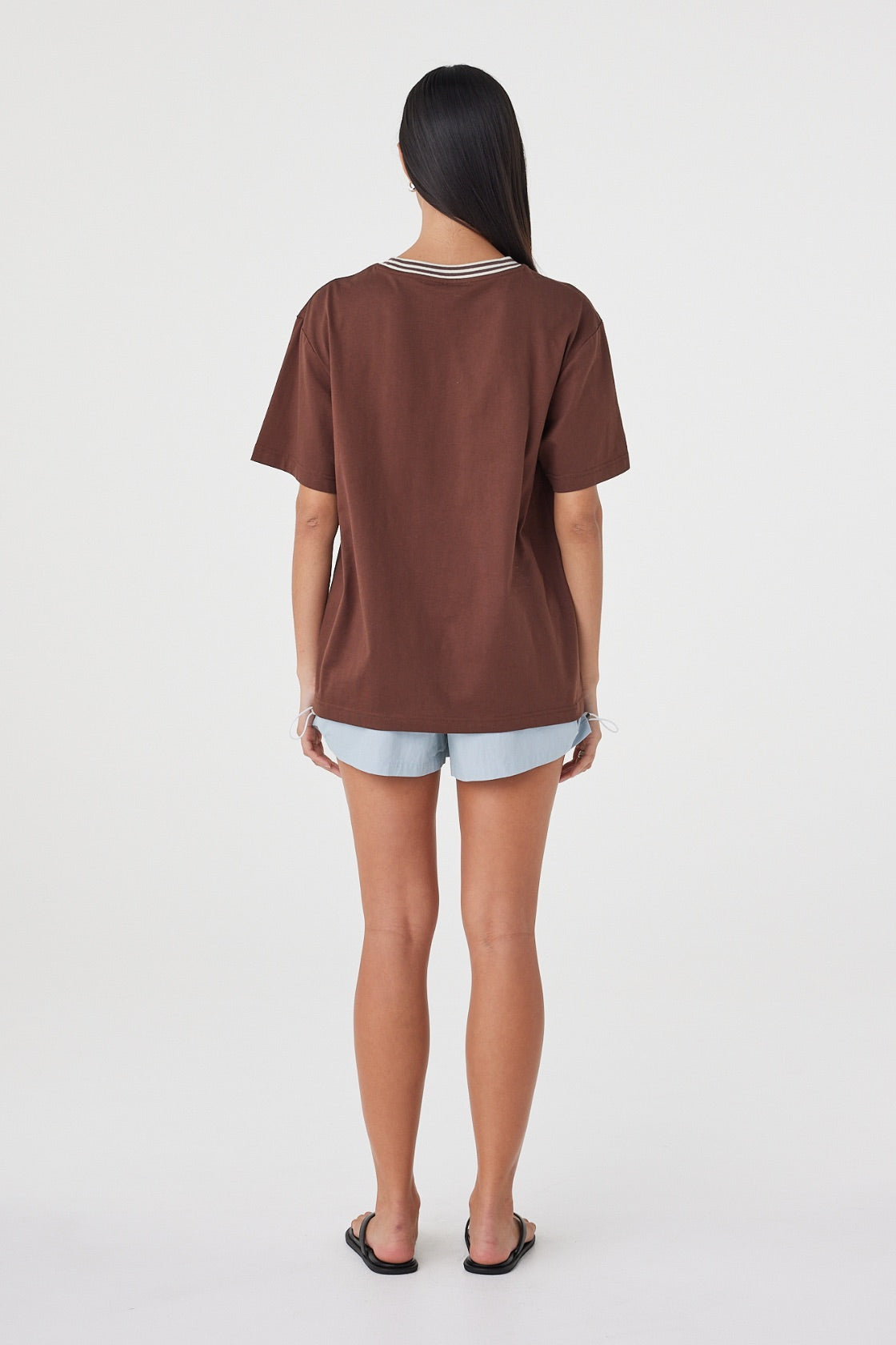 Kylen Tee in Espresso & Cream styled with pale blue shorts, full-length back view showing the relaxed fit and longer hem.