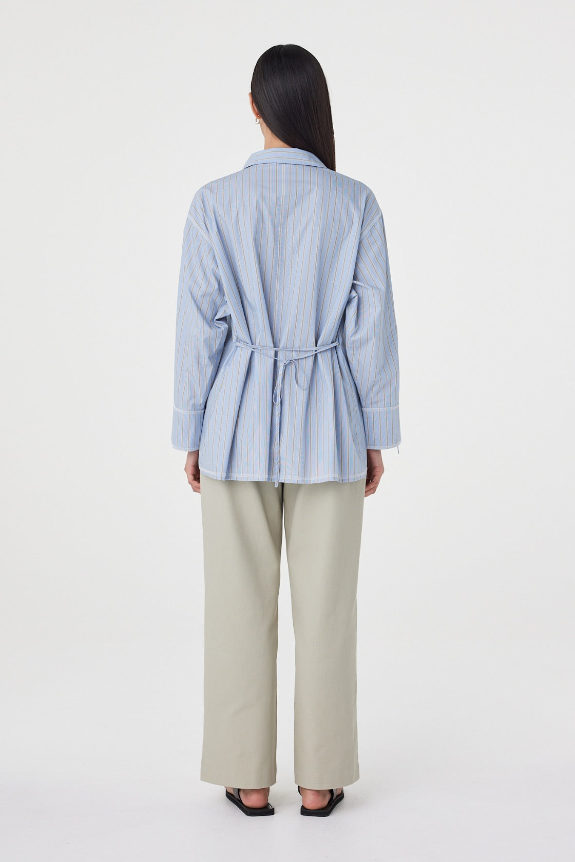 Back view of the Blair Shirt in Blue Taupe Stripe showcasing the adjustable waist tie, relaxed silhouette and vertical stripe detailing.