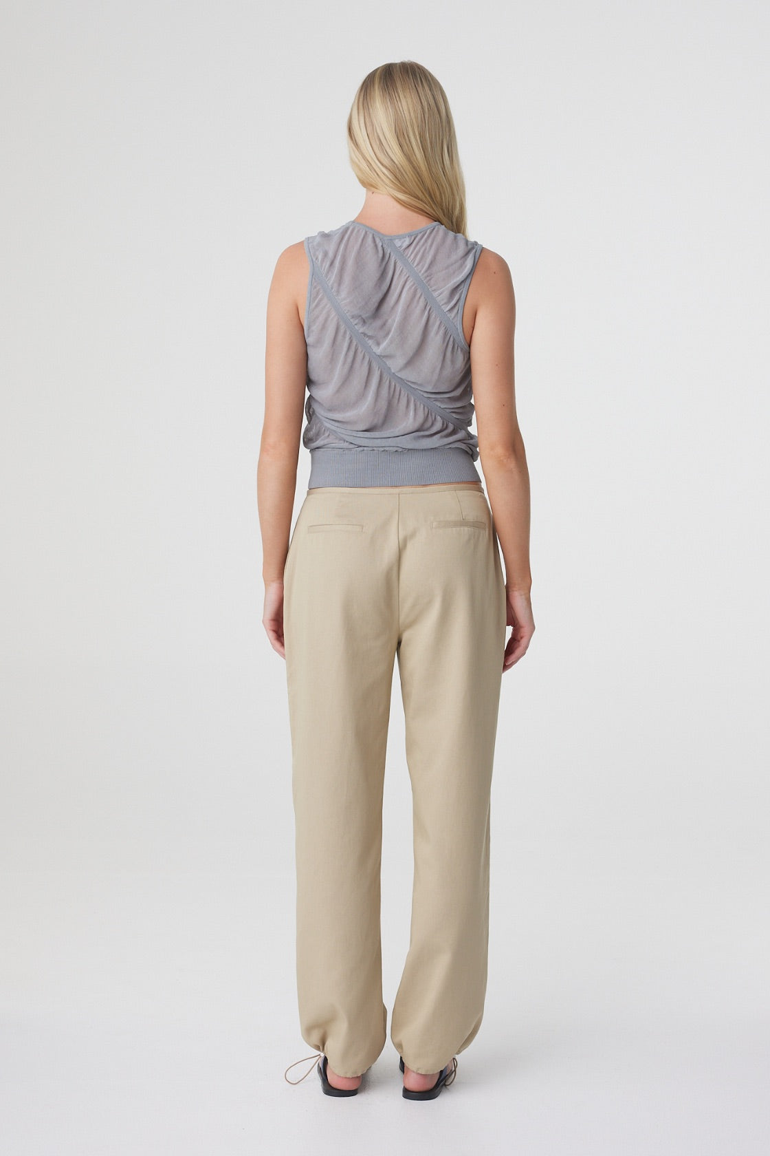 Hana Top in Mist, back view styled with cream trousers, showing the fitted sleeveless silhouette and sheer finish.