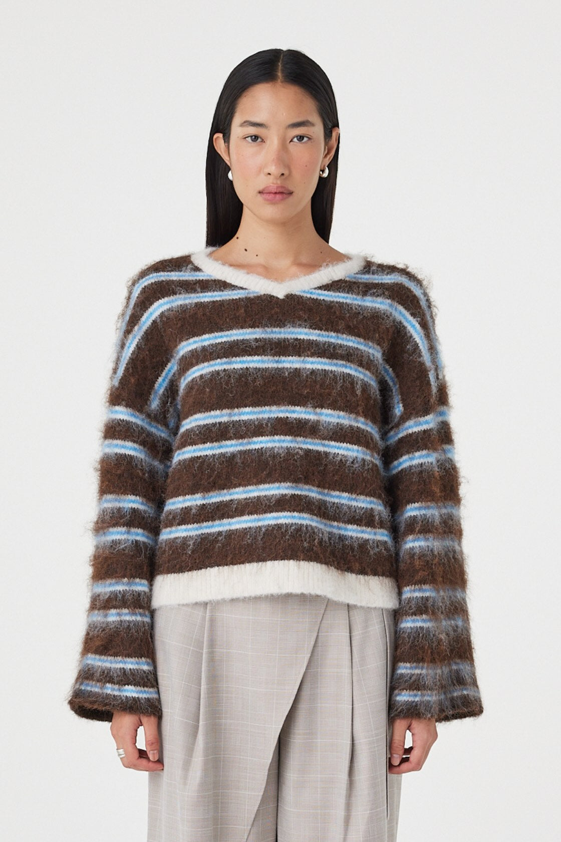 Front view of the Lucca Sweater in Espresso & Blue Stripe featuring a fluffy knit texture, relaxed silhouette and soft blue stripe detailing, styled with light taupe wide-leg trousers.