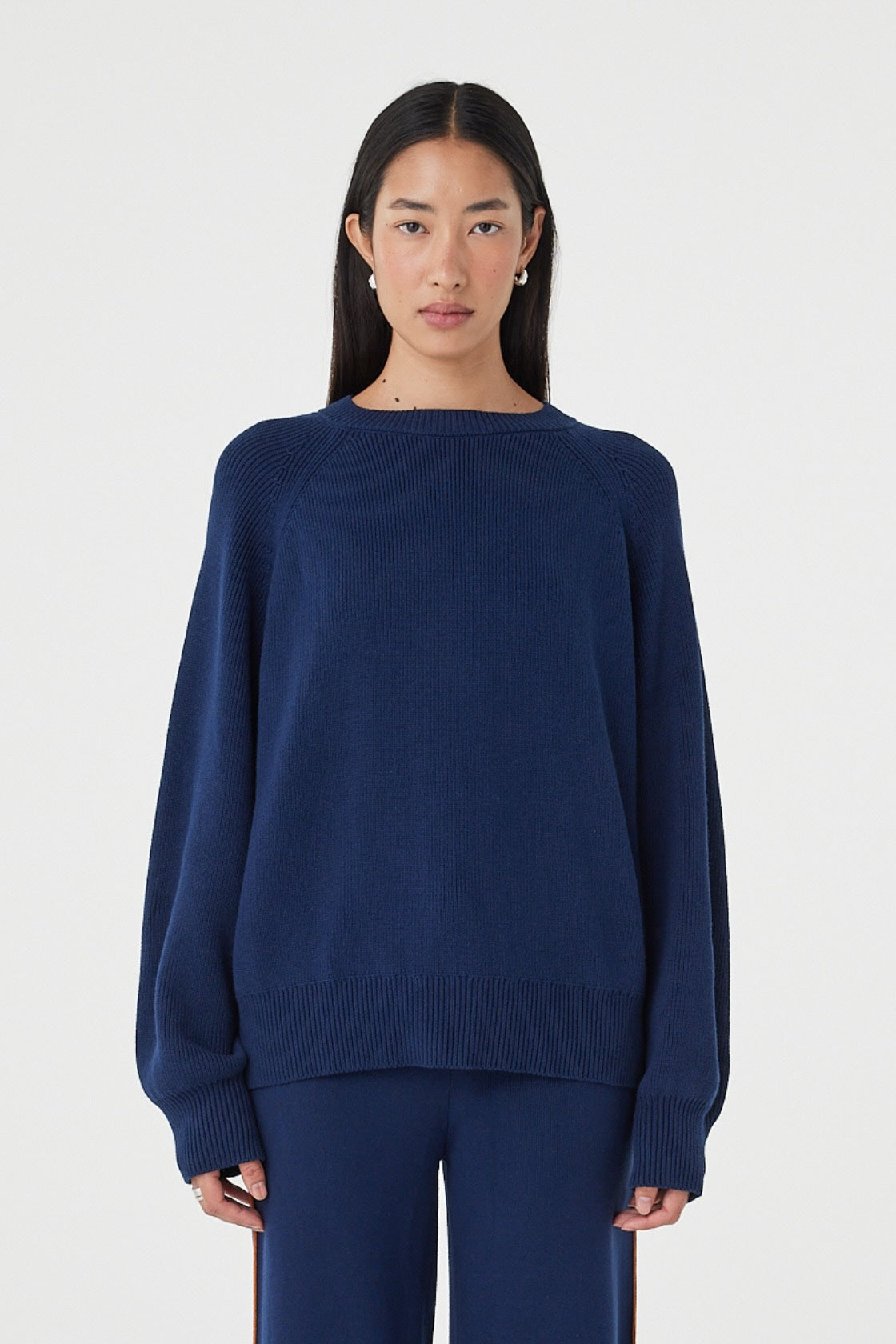 Front view of the Aubrey Sweater in Navy featuring a relaxed silhouette, fine knit texture and gathered neckline detailing, styled with matching navy knit pants.