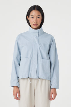 Front view of the Addie Jacket in Pale Blue featuring a funnel neckline, concealed zip closure and oversized front patch pockets, styled with wide-leg trousers.