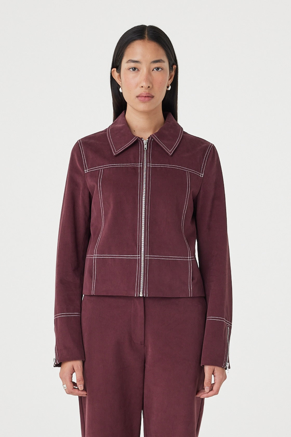 Front view of the Benny Jacket in Merlot featuring contrast stitching, lapel collar and silver zip-front closure, styled with matching merlot pants.