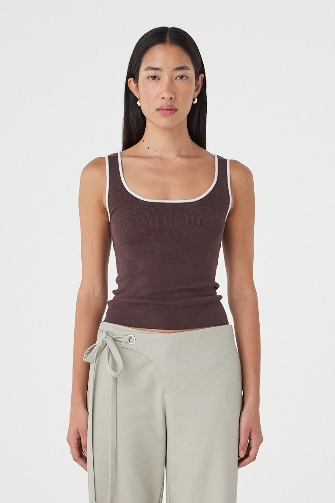 Front view of the Kaya Tank in Espresso & Cream featuring contrast trim, a slim-fitting silhouette and soft organic cotton knit, styled with light sage wrap pants.
