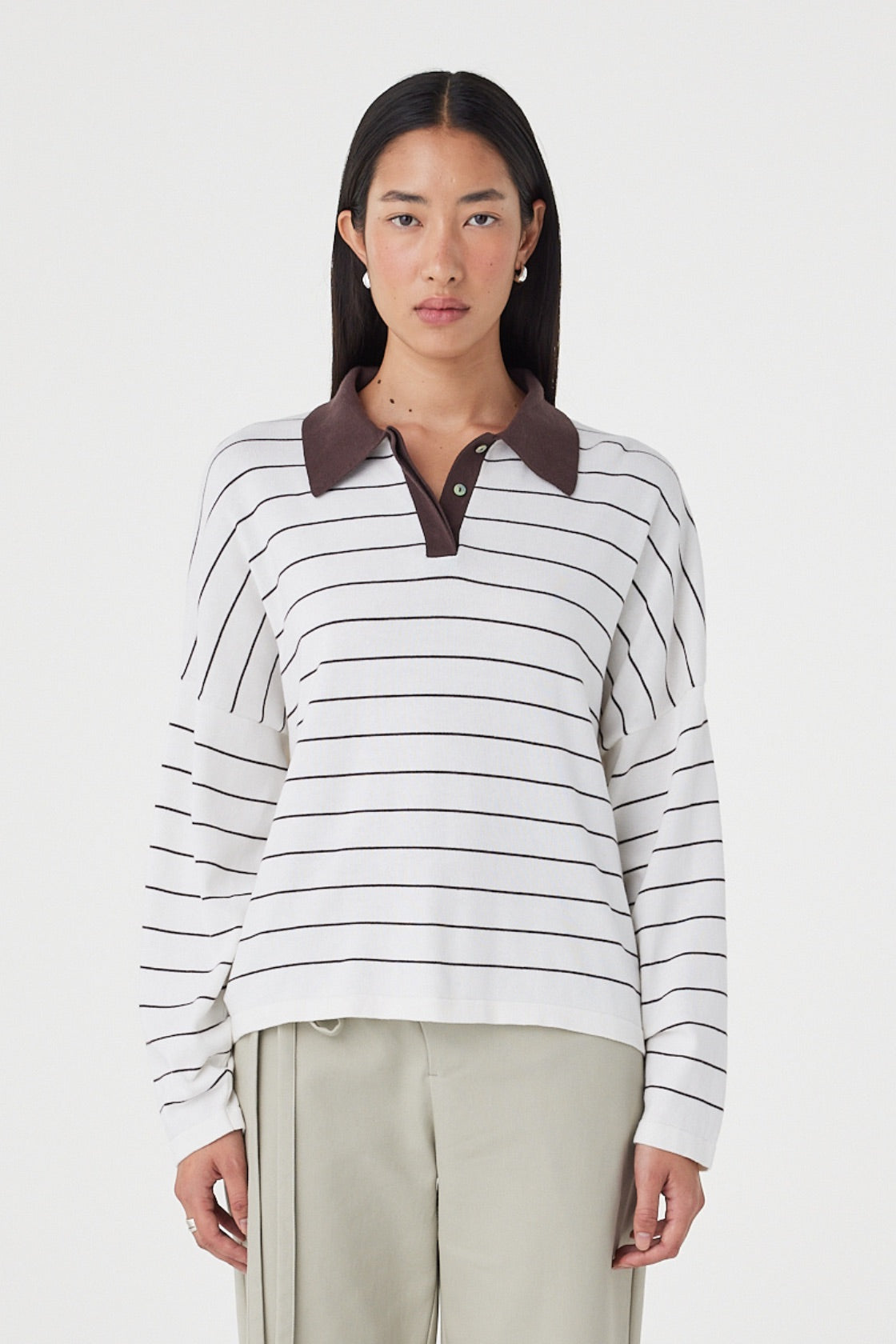 Front view of the Zia Tie Knit Jersey in Cream & Espresso featuring a contrast espresso collar, fine stripe detailing and an oversized organic cotton knit, styled with sage trousers.