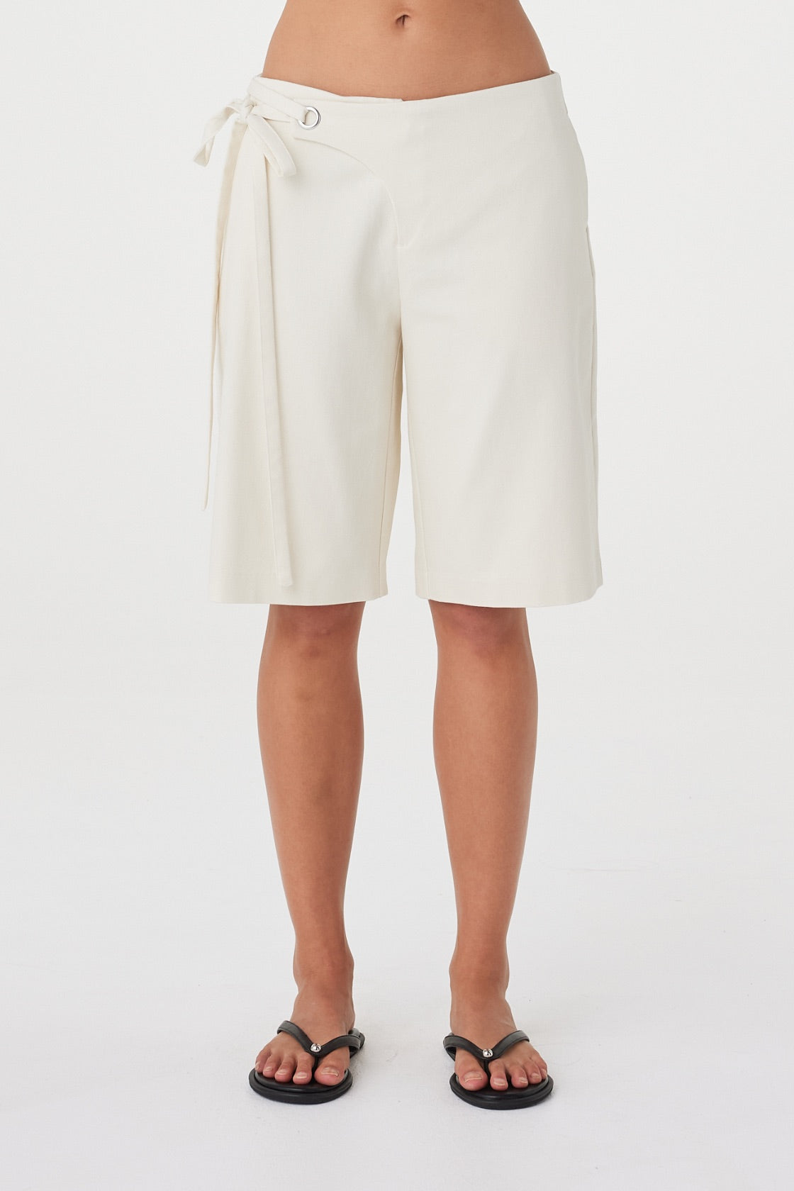 Front view of the Lucia Tie Bermuda Short in Bone highlighting the fabric overlap waistband, silver eyelets and double tie detail.
