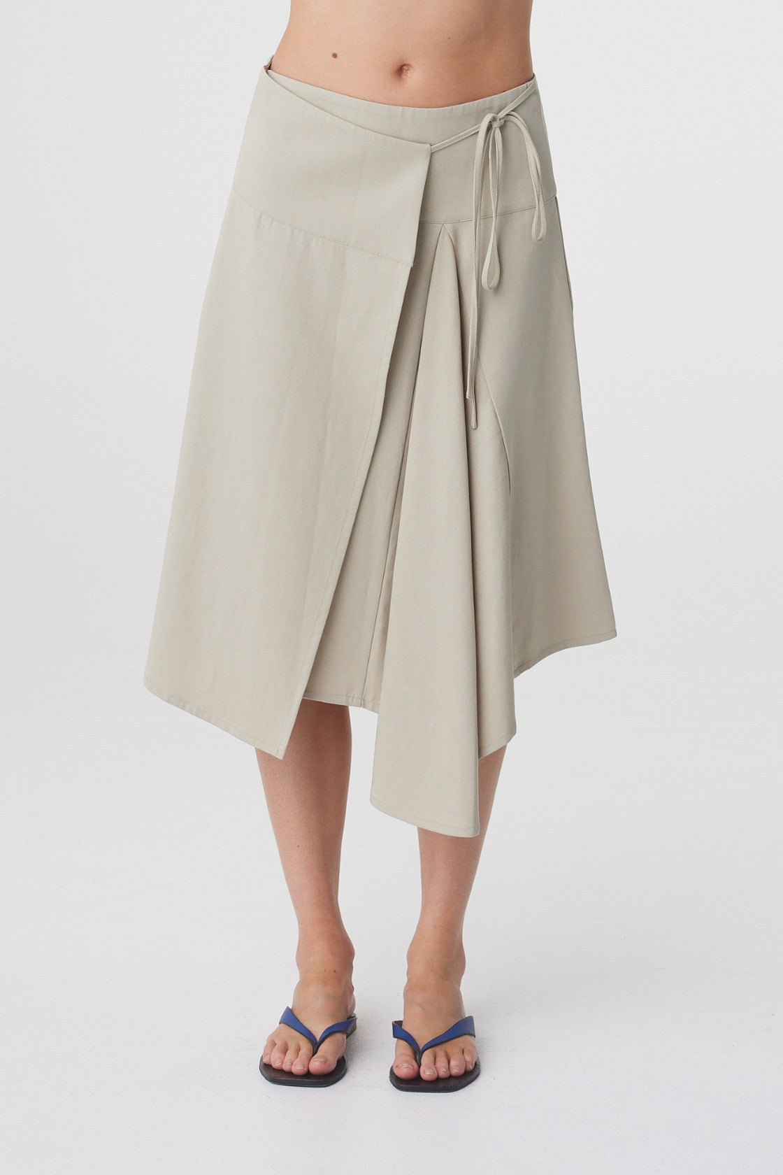 Anya Skirt in Taupe, close front view highlighting the deep waistband, wrap construction, tie detail and asymmetric hemline.