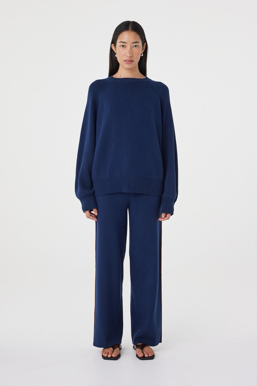 Front view of the Milan Pant in Navy & Tumeric featuring a relaxed wide-leg silhouette, contrast side stripes and drawcord waistband, styled with the matching Aubrey Sweater.