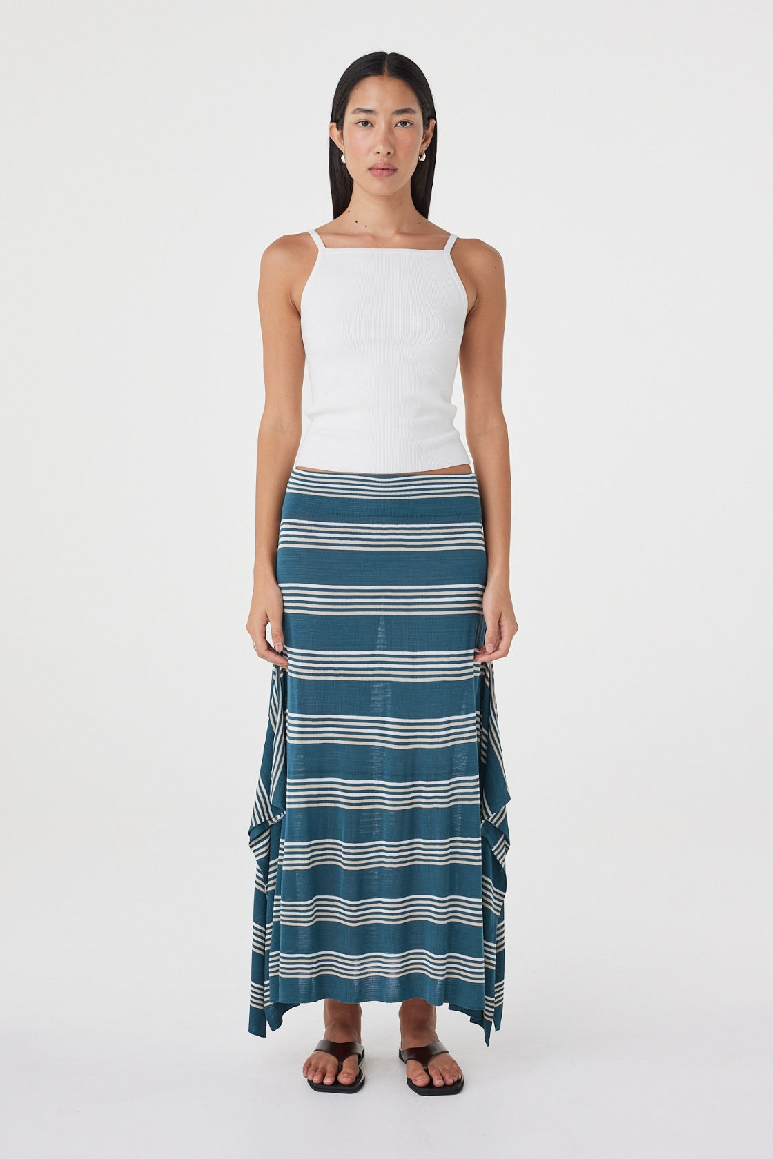Front view of the Lex Skirt in Teal Stripe featuring a custom stripe print, elasticated waistband and flowing handkerchief silhouette, styled with a white tank.
