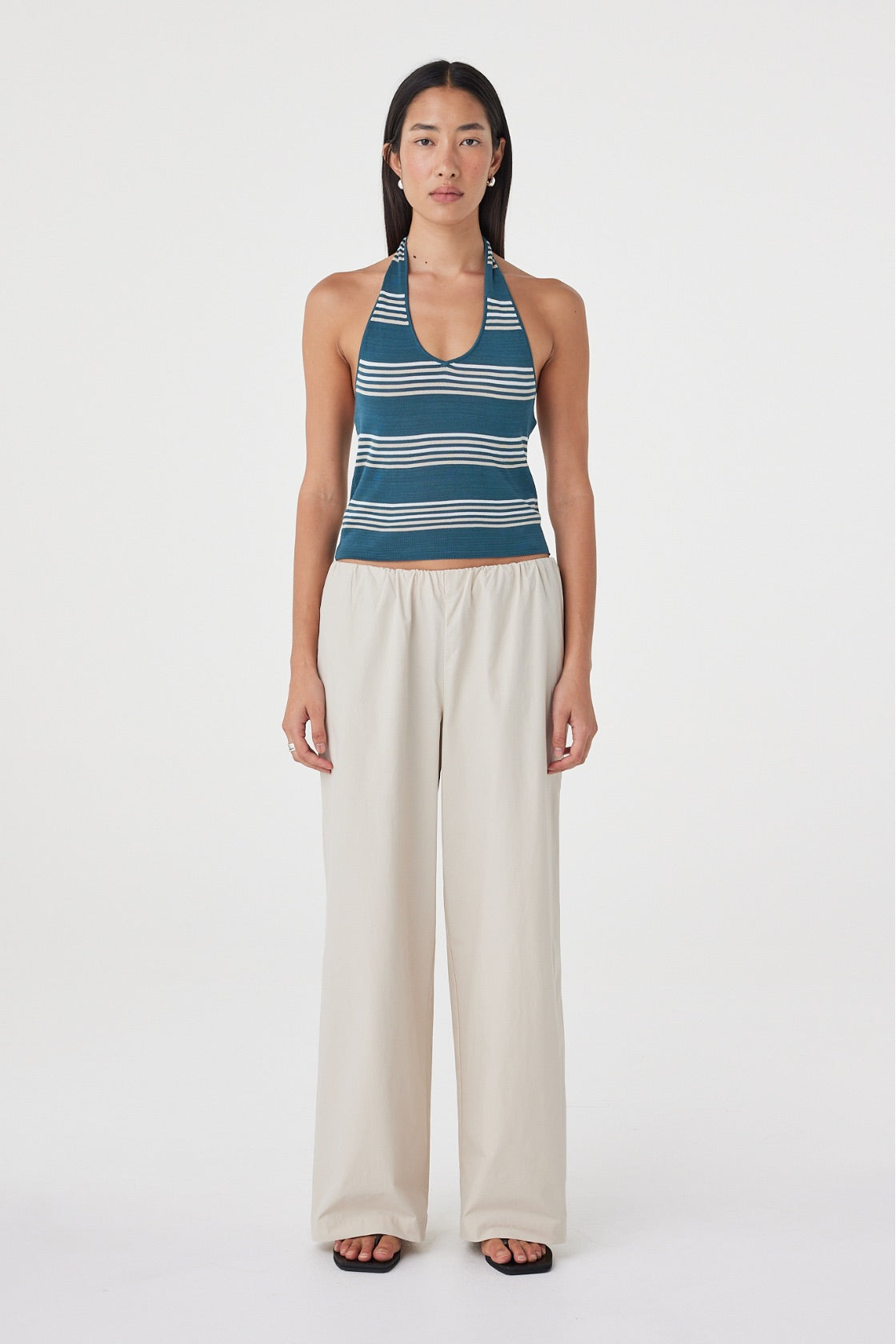 Front full-length view of the Annika Pant in Taupe styled with a blue and cream striped tank and sandals, showing the relaxed wide leg silhouette.