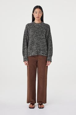 Full-length front view of the Solene Sweater in black and taupe featuring a chunky marled knit texture, oversized silhouette and ribbed hem styled with espresso pants